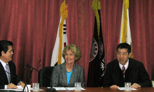 Picture of Drs. Burgstahler and Iwabuchi at a table in front of several flags.