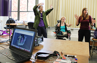 Three students modeling with mapping equipment.