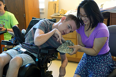 An intern works with a student in a geology classroom.