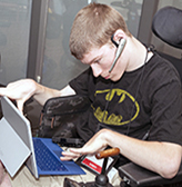 A student uses a headset and a tablet with an attachable keyboard.