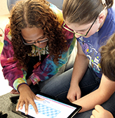 Two deaf students use a tablet.