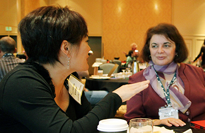 Two faculty members talk while sitting.