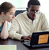 A mentor works with a student on a computer project