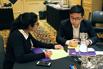 Two people sit at a table discussing the topic at hand.