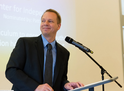 Photo of DO-IT program manager Scott Bellman standing at a podium to give an acceptance speech