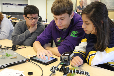 Three students view a tablet.