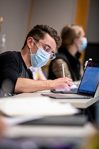 A student in a mask taking notes.