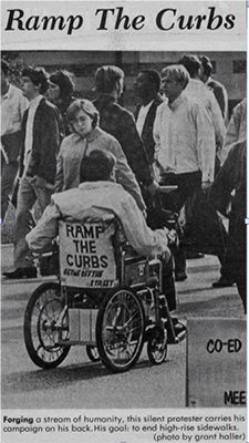 A newspaper clipping showing a man in a wheelchair with "Ramp the Curbs"on the back of his chair