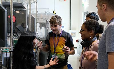 An educator shows students how to use a 3-D printer